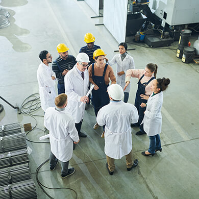 A group of workers wearing helmets on the production floor